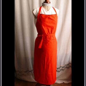 Tablier de potier (deux pans fendus pour les jambes) en toile légère rouge, ceinture longue pouvant se nouer à l'avant. Vu de face sur un mannequin de couture