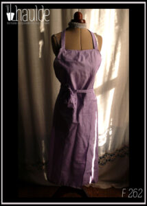 Tablier de potier (deux pans fendus pour les jambes) en toile légère mauve, ceinture longue pouvant se nouer à l'avant. Vu de face sur un mannequin de couture