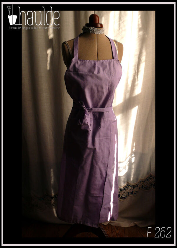 Tablier de potier (deux pans fendus pour les jambes) en toile légère mauve, ceinture longue pouvant se nouer à l'avant. Vu de face sur un mannequin de couture