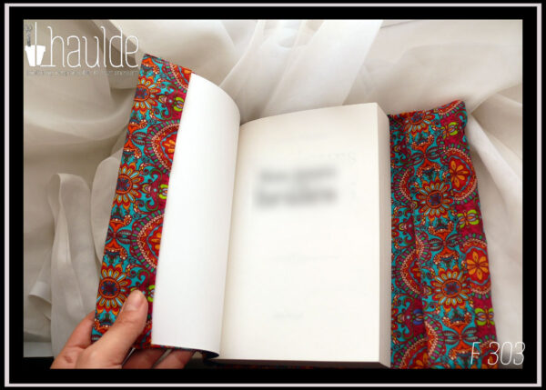 Protège livre en coton imprimé motifs psychédéliques sur fond bleu vert, dominante orange. Vue du rabat sur le devant du livre ouvert