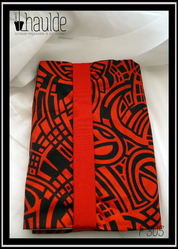 Protège livre en tissu rouge et noir, motifs abstraits, courbes parallèles Vu fermé par son gros élastique rouge