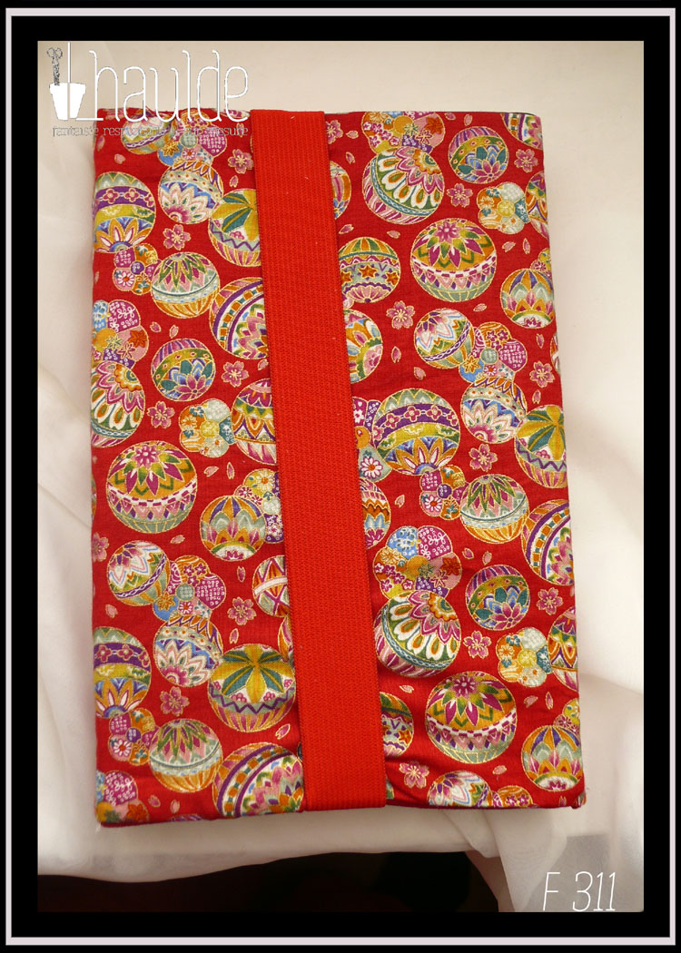 Protège livre en tissu rouge imprimé temari (balles brodées japonaises) multicolores Vu fermé par son gros élastique rouge