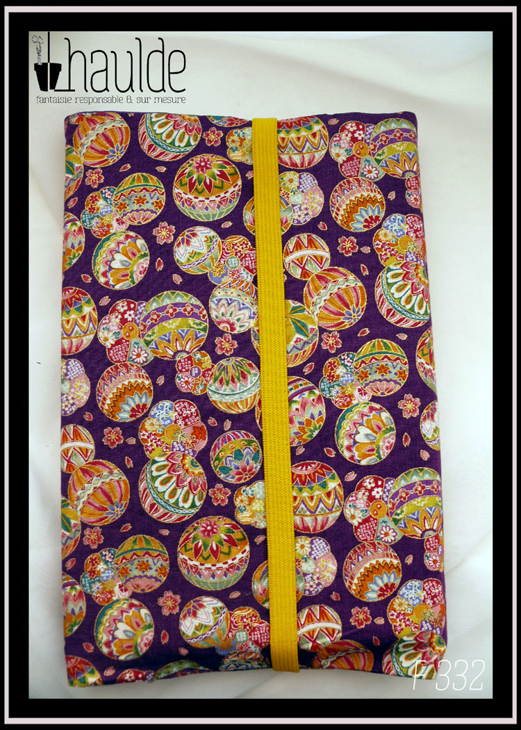 Protège livre en tissu violet imprimé temari (balles brodées japonaises) multicolores Vu fermé par un élastique jaune