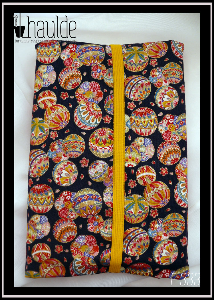 Protège livre en tissu bleu marine très foncé imprimé temari (balles brodées japonaises) multicolores Vu fermé par un élastique jaune