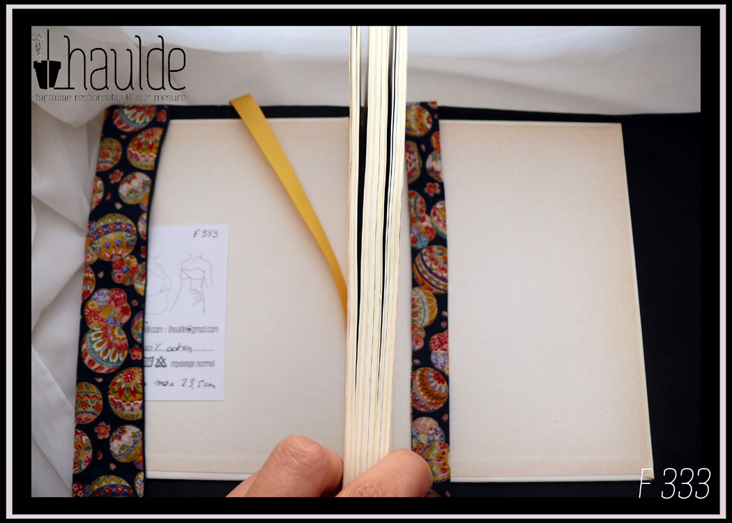 Protège livre en tissu bleu marine très foncé imprimé temari (balles brodées japonaises) multicolores Vu ouvert, intérieur noir, signet jaune