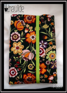 Protège livre en coton noir imprimé fleurs multicolores, vu fermé par un élastique vert anis