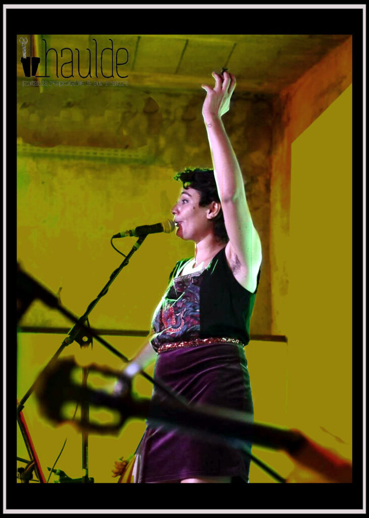 femme debout de profil sur une scène en train de chanter, portant une robe en velours et en toile imprimée
