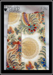 Protège livre en tissu écru imprimé motifs végétaux et floraux d'esthétique asiatique multicolores et bordés de doré. Vu fermé