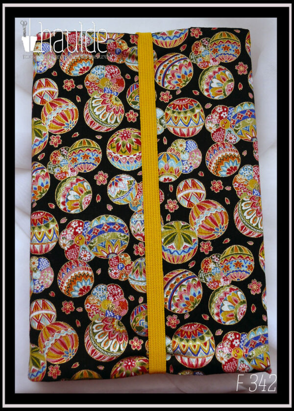 Protège livre en tissu noir imprimé temari (balles brodées japonaises) multicolores Vu fermé par un élastique jaune