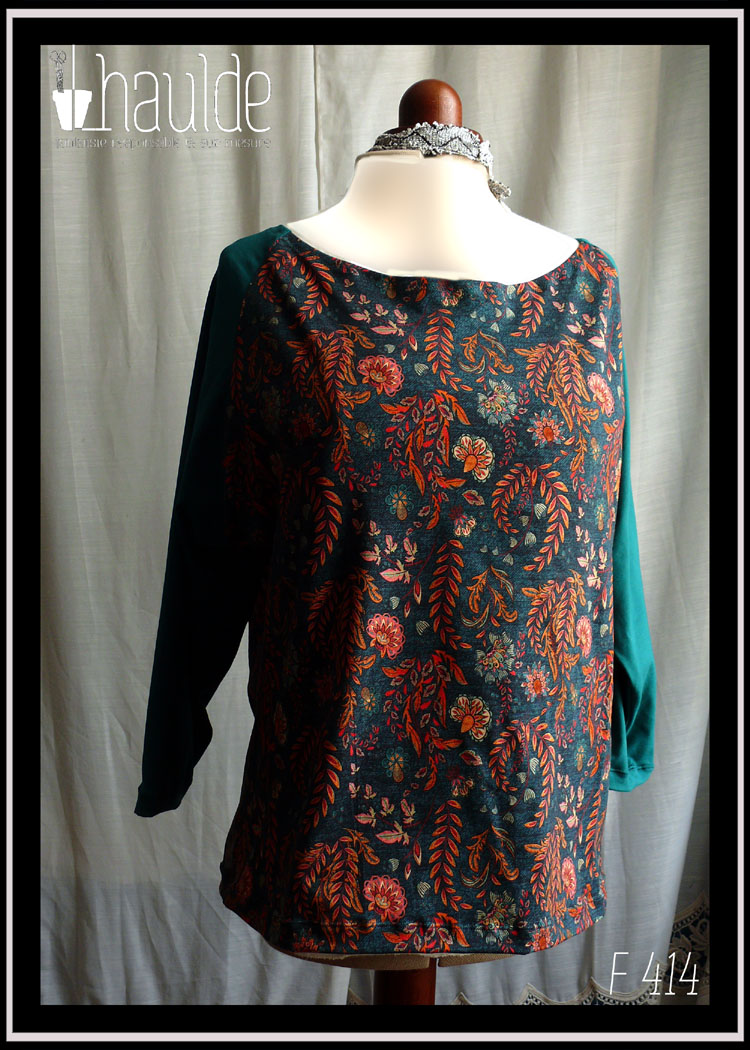 Haut manches longues encolure dégagée, centre devant et dos en tissu bleu mariné imprimé feuilles d'automne et fleurs (dominante orange foncé, bleu et rose) et manches vert canard Vu de face sur un mannequin de couture