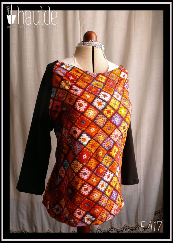 Haut en jersey imprimé carrés de crochet multicolores, dominante rouge et orange, manches raglan longues en jersey noir Vu de face sur un mannequin de couture
