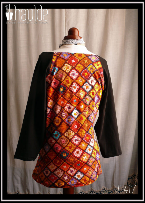 Haut en jersey imprimé carrés de crochet multicolores, dominante rouge et orange, manches raglan longues en jersey noir Vu de dos sur un mannequin de couture
