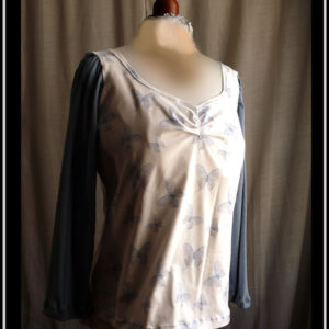 haut en jersey blanc imprimé papillons bleus (comme des aquarelles) manches longues en maille pointelle bleu jean Buste légèrement plissé Vu de face sur un mannequin de couture
