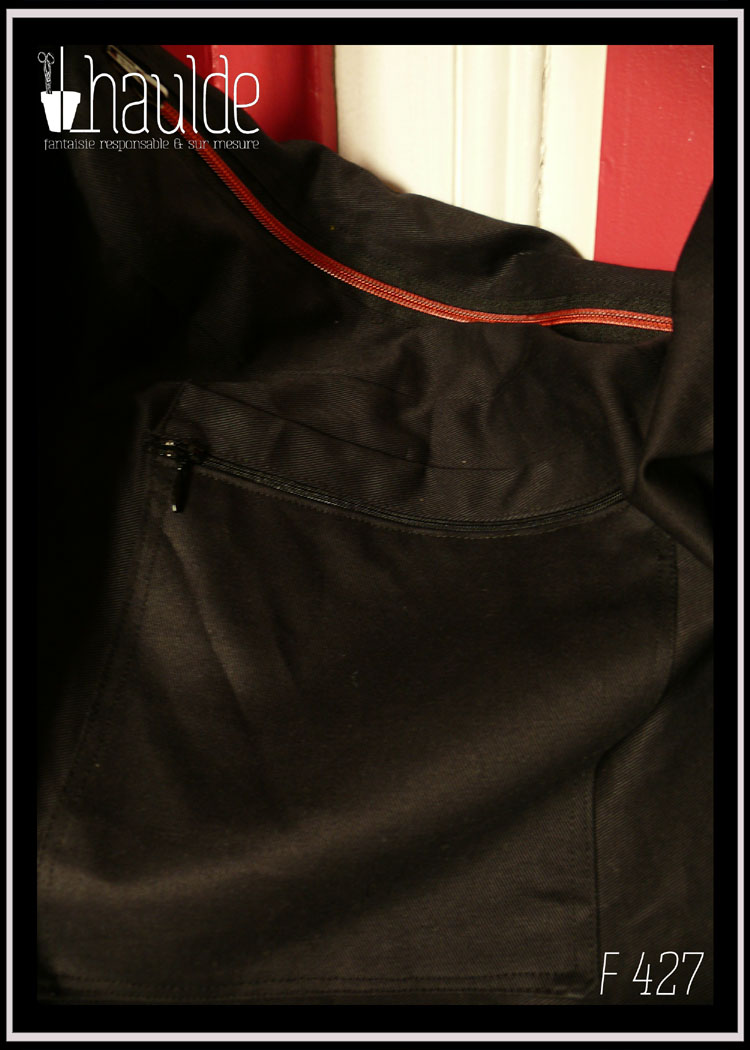 Sac en sergé noir, grand format horizontal à bandoulière, avec des appliqués en forme de pensées rouges avec leurs feuilles. Le centre des fleurs, les contours et les tiges sont brodés à la machine Vue de la poche extérieure zippée