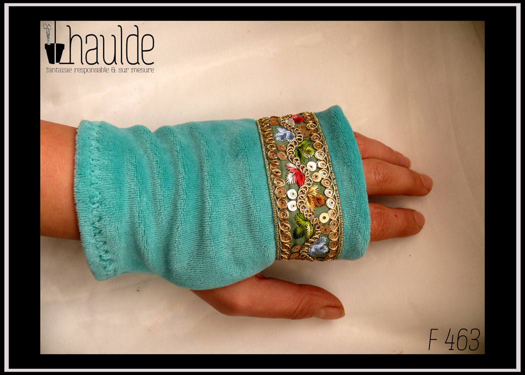 Mitaine en velours bleu clair garnie au niveau des phalanges d'un galon brodés de feuilles bleu vert et rouge et de petits sequins dorés Vue de dessus, portée