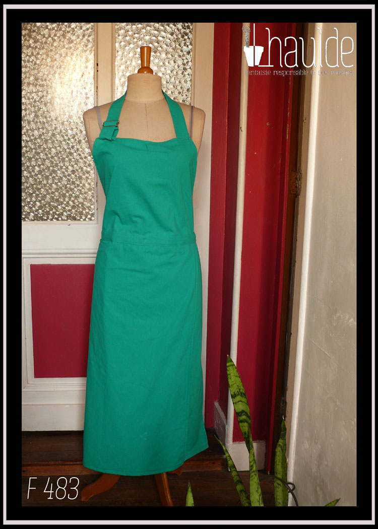 Tablier de potier vert moyen assez éclatant, vu sur un mannequin de couture dans un couloir.