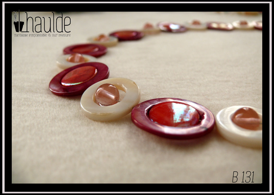 Collier composé de cercles de nacre blanc avec une perle de cristal rose en leur centre alternés avec des cercles de nacre rouges avec un palet de nacre rose irisé en leur centre Vue en gros plan du collier