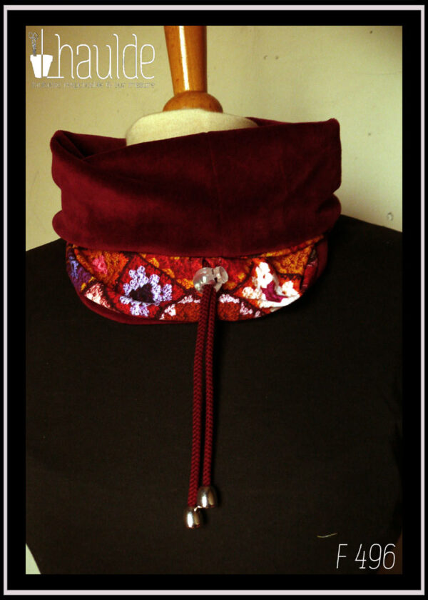 cache-col montant en jersey imprimé "granny squares", des carrés de crochets multicolores, dominante rouge. Doublure en velours rouge bordeaux, cordon rouge bordeaux avec des clochettes pour protéger les bouts et un serre-cordon transparent. Vu avec le velours replié sur le jersey, sur un mannequin de couture