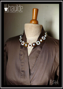 Détail de l'encolure avec un collier en cercles de nacre et pierres naturelles (référence B 127) Chemisier manches longues col châle croisé noué dans le dos en satin de coton marron glacé