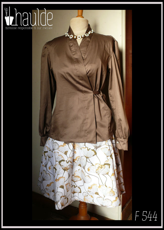 Chemisier manches longues col châle croisé noué dans le dos en satin de coton marron glacé Vu sur un mannequin de couture avec une jupe blanche imprimé feuilles de ginkgo transparentes dans les tons marrons et roux (référence de la jupe : F 545)