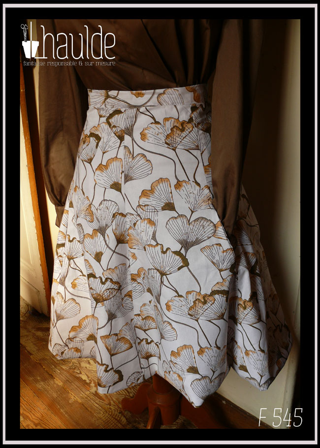 jupe à 6 pans évasés, blanche imprimé feuilles de ginkgo transparentes dans les tons marrons et roux Vu sur un mannequin de couture, la manche du chemisier rentre dans une des poches de la jupe