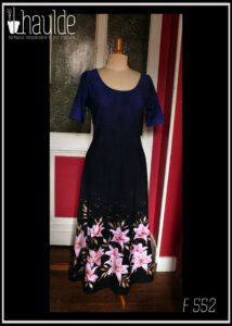 Robe longue à manches courtes en jersey. Ajustée jusqu'à la taille puis plus ample jusqu'en bas. Le tissu est dégradé du bleu nuit en haut jusqu'au noir en bas avec de gros lys roses à feuillage doré sur le bas de la jupe Vue de face sur un mannequin de couture