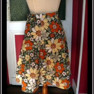 jupe à 6 pans en tissu vert foncé imprimé grosses fleurs jaunes pâles, orange et blanches Vue de face sur un mannequin de couture