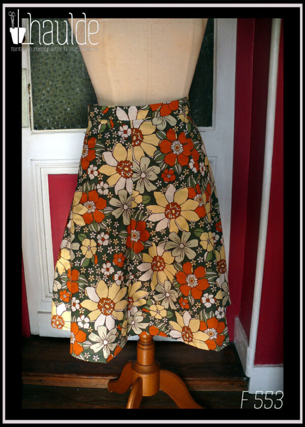 jupe à 6 pans en tissu vert foncé imprimé grosses fleurs jaunes pâles, orange et blanches Vue de face sur un mannequin de couture