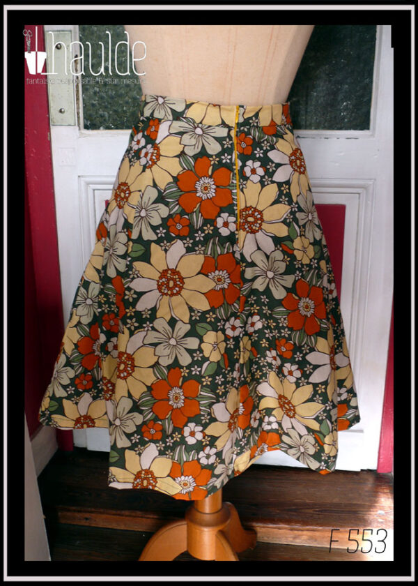 jupe à 6 pans en tissu vert foncé imprimé grosses fleurs jaunes pâles, orange et blanches Vue de dos sur un mannequin de couture