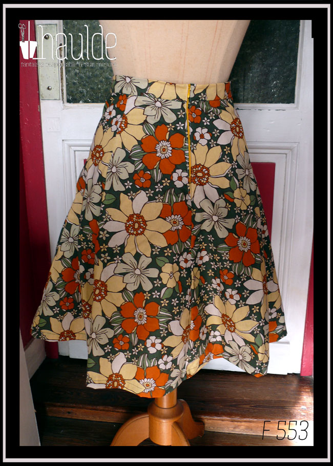 jupe à 6 pans en tissu vert foncé imprimé grosses fleurs jaunes pâles, orange et blanches Vue de dos sur un mannequin de couture