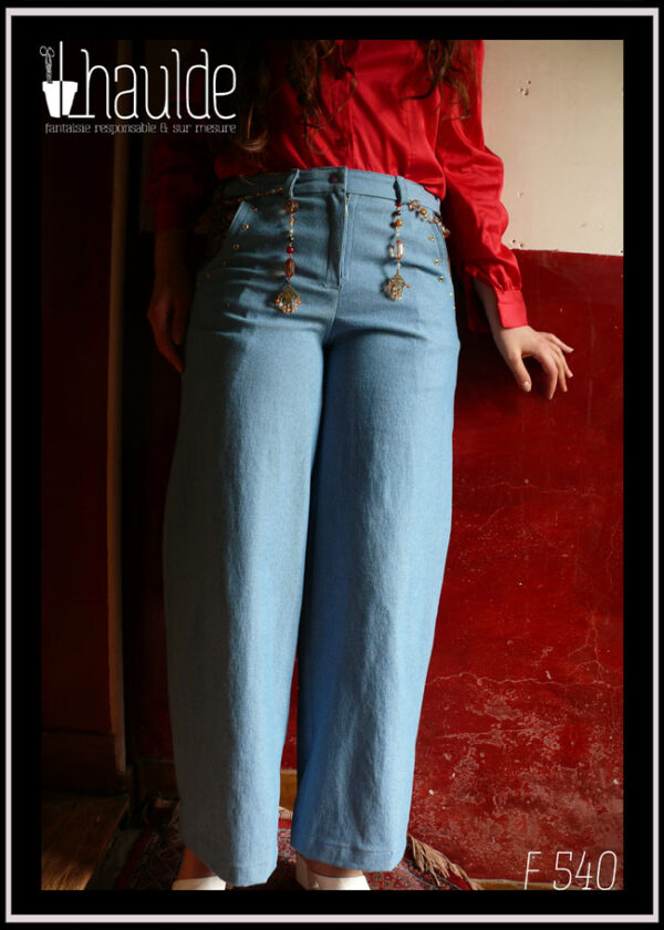 Jean bleu clair avec une ceinture bijou dont les extrémités pendant sur l'avant du jean Vu porté avec un chemisier en satin de coton rouge cerise