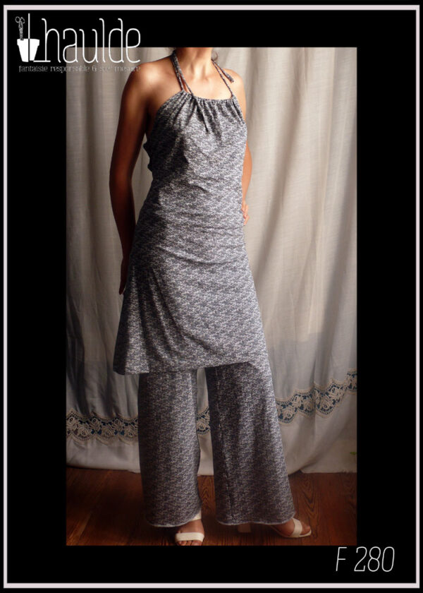 Femme debout portant la robe F 195 et un pantalon dans le même jersey bleu très foncé, imprimé graphique blanc, dont on ne voit que les jambes amples