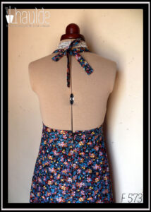 Robe dos nu en tissu fond noir imprimé petites fleurs jaunes, roses et orange, feuillage bleu paon et rouge foncé Vue de dos sur un mannequin de couture