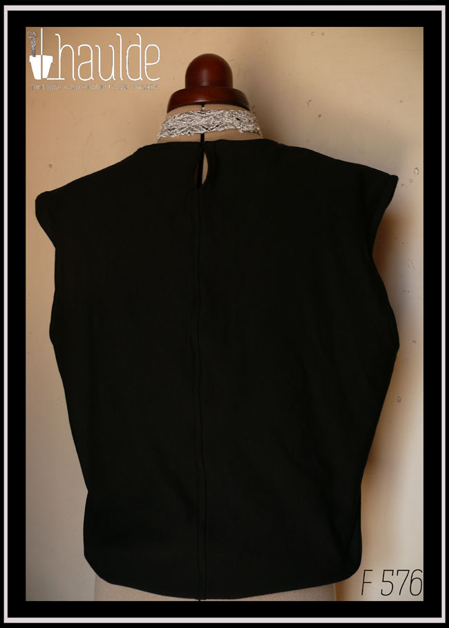 Haut sans manche en french terry noir, ras du cou, façon blouse avec un bas élastiqué qui renforce l'aspect bouffant vu de dos sur un mannequin de couture, il y a une petite fente au niveau du coup pour permettre un enfilage plus facile (se ferme avec un crochet)