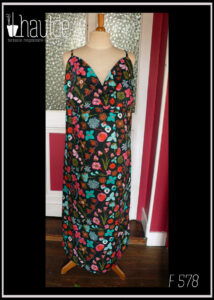 Robe dos nu en popeline noire imprimé fleurs à dominante rose-rouge et turquoise Décolleté en V courbe, bretelles fines Vue de face sur un mannequin de couture