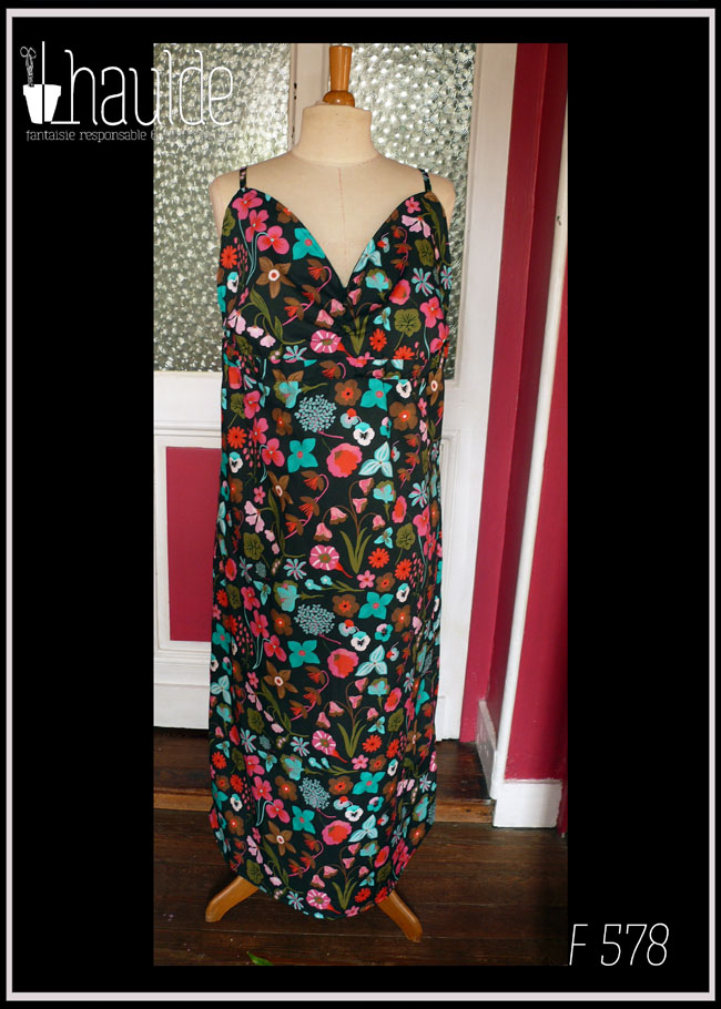 Robe dos nu en popeline noire imprimé fleurs à dominante rose-rouge et turquoise Décolleté en V courbe, bretelles fines Vue de face sur un mannequin de couture