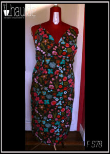 Robe dos nu en popeline noire imprimé fleurs à dominante rose-rouge et turquoise Décolleté en V courbe, bretelles fines Vue de face sur un mannequin de couture