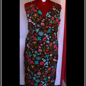 Robe dos nu en popeline noire imprimé fleurs à dominante rose-rouge et turquoise Décolleté en V courbe, bretelles fines Vue de face sur un mannequin de couture