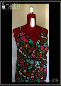 Robe dos nu en popeline noire imprimé fleurs à dominante rose-rouge et turquoise Décolleté en V courbe, bretelles fines Vue de détail du buste sur un mannequin de couture