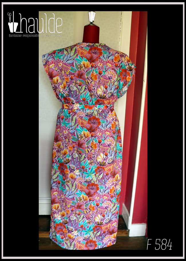 Robe longue manches très courtes en tissu imprimé fleurs stylisées multicolores (dominante rose et orange-rouge) et feuillage turquoise sur fond rose.. Vue de dos sur un mannequin de couture