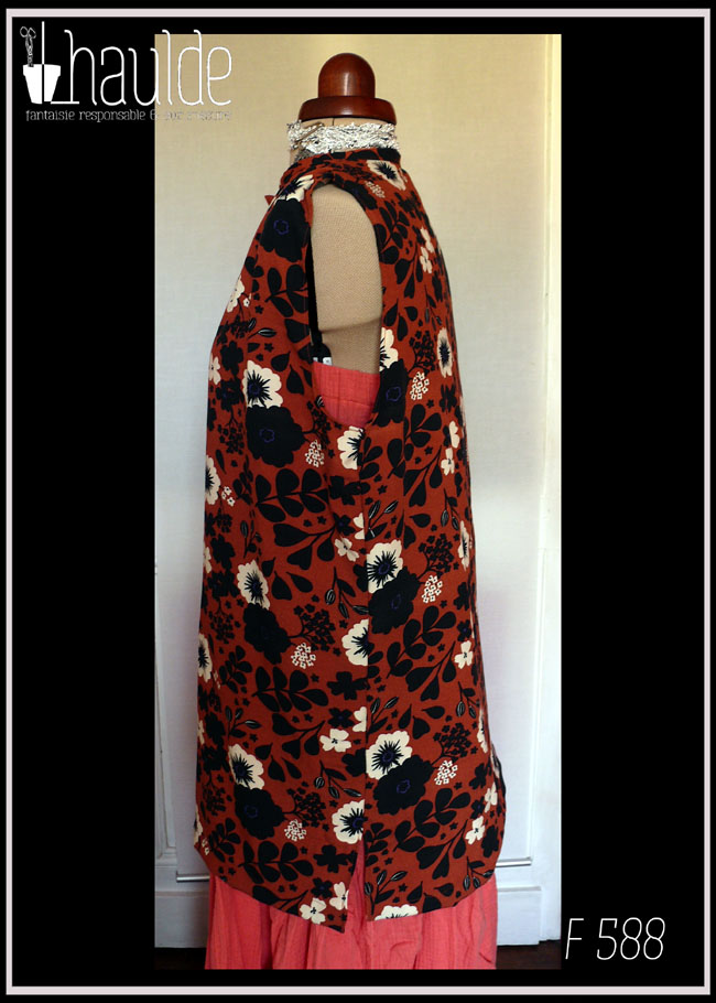 Haut sans manches, froncé aux épaules en viscose terracotta imprimée fleurs blanches et silhouettes de fleurs et feuilles noires Boutons en résine contenant des fleurs séchées oranges. Col à liseret simple Vu de profil sur un mannequin de couture