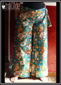 Pantalon ample en coton vert canard imprimé de camélia japonais blancs, vermillon, or et bleus cernés d'or Il est noué des deux côté à la taille, ici avec les pans de la ceinture qui pendent Vu porté, de face