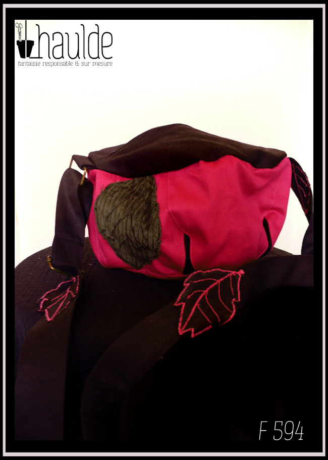 Vue de face du sac boule à bandoulière, Fond rose fuchsia, dessus et bandoulière en sergé noir Bandoulière réglable garnie de feuilles de sergé noir à nervures rose, feuilles en velours cotelé kaki plaquée sur le sac