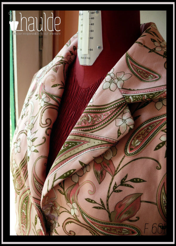 Vue de détail de l'encolure. tissu sergé rose pâle à motifs végétaux et paisley dans les tons verts kakis et roses avec des fleurs blanches