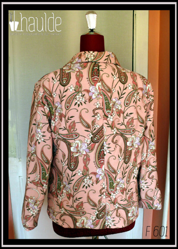 La veste vue de dos sur un mannequin de couture Manches longues, tissu sergé rose pâle à motifs végétaux et paisley dans les tons verts kakis et roses avec des fleurs blanches