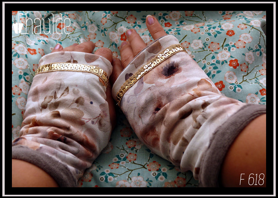 Mitaines en jersey blanc imprimé fleurs aquarellées dans les tons oranges-gris. Manchettes en velours gris. Un galon de sequins carrés dorés sur deux rangs décore au niveau des phalanges Vue de la paire portée