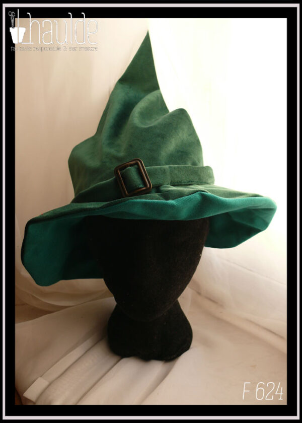 Chapeau de sorcière à haut bout pointu et large rebord en velours vert foncé avec un ruban du même velours et une boucle de ceinture au centre en acier couleur bronze Vu porté par une tête de mannequin