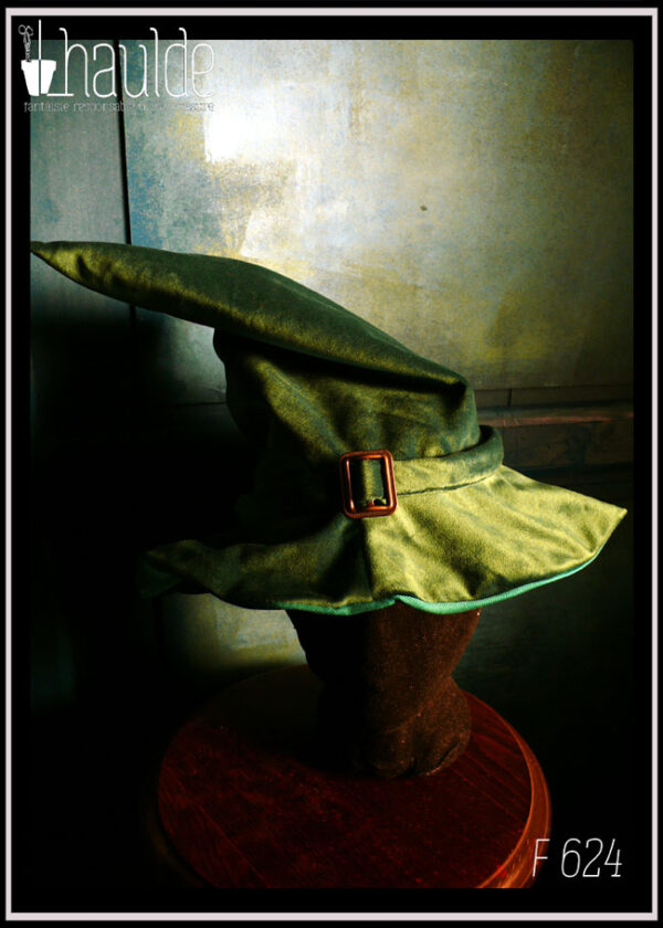 Chapeau de sorcière à haut bout pointu et large rebord en velours vert foncé avec un ruban du même velours et une boucle de ceinture au centre en acier couleur bronze Vu porté par une tête de mannequin
