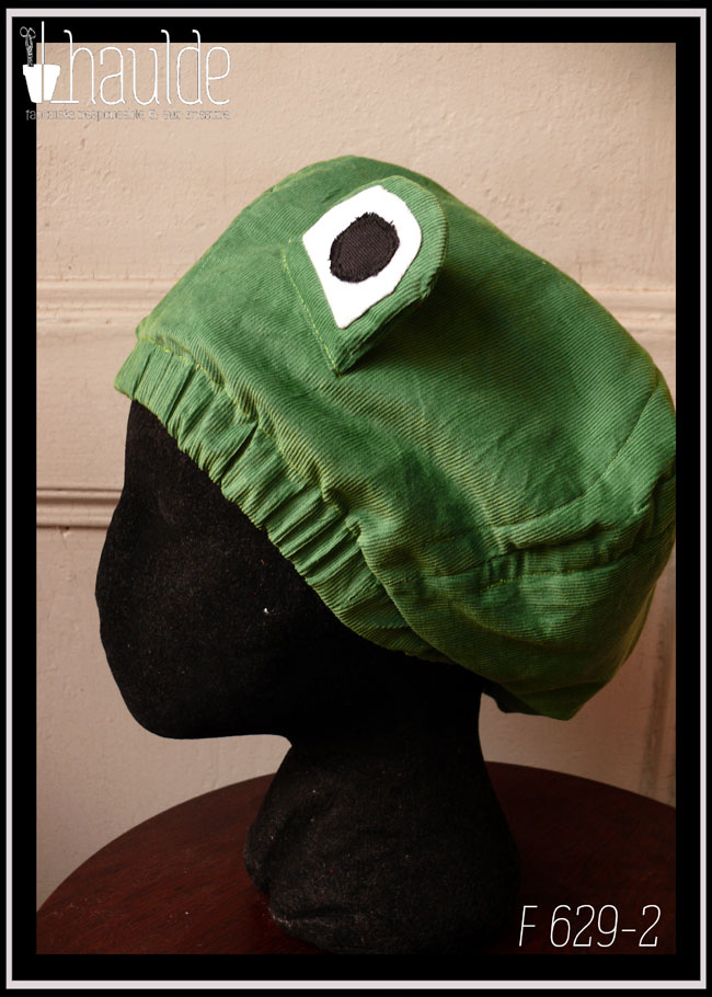 Bonnet en velours milleraies vert clair avec deux yeux sur le dessus pour figurer une tête de grenouille Vu de profil sur une tête de mannequin