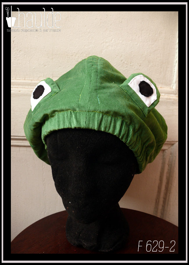 Bonnet en velours milleraies vert clair avec deux yeux sur le dessus pour figurer une tête de grenouille Vu de face sur une tête de mannequin